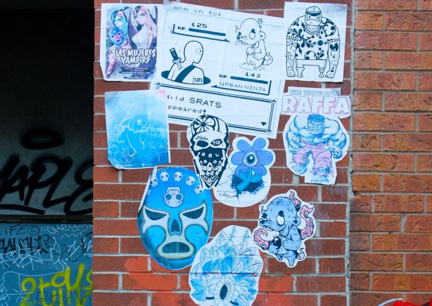 pasteups in a group on a brick wall, urban ninja squadron, mask, daisy with one eye, 