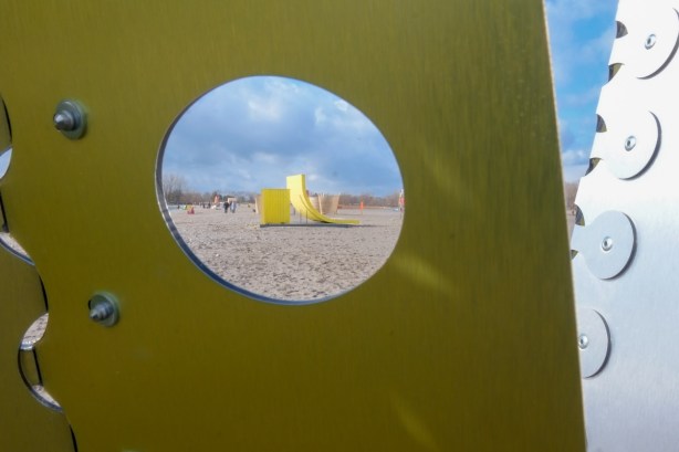 looking through the holes of a metal art installation structure, beach