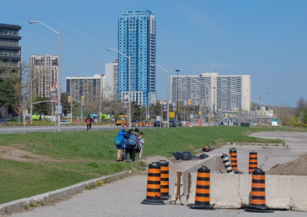 a small group of boys walking along the grass beside Eglinton Ave on the east side of Don Mills