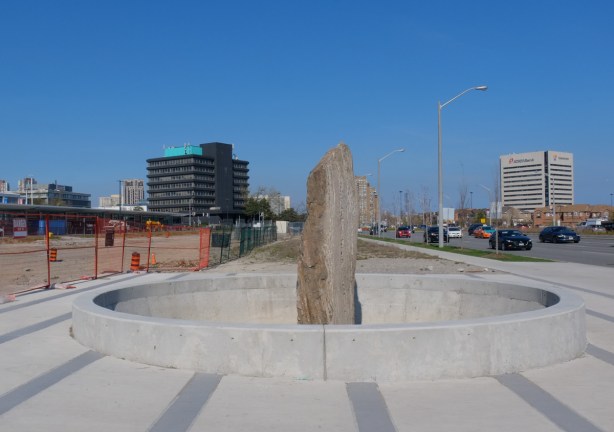 a rock pillar stands upright, in the center of a concrete circle