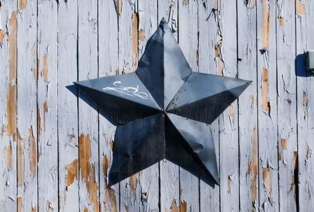 on a wood fence, a large three dimensional metal star