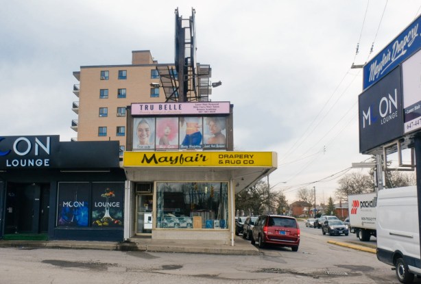 two storey store front on Lawrence with lowrise apartment building in the background