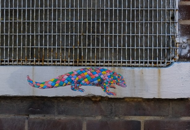on a concrete window sill, exterior, a graffiti chameleon coloured with many different diamonds