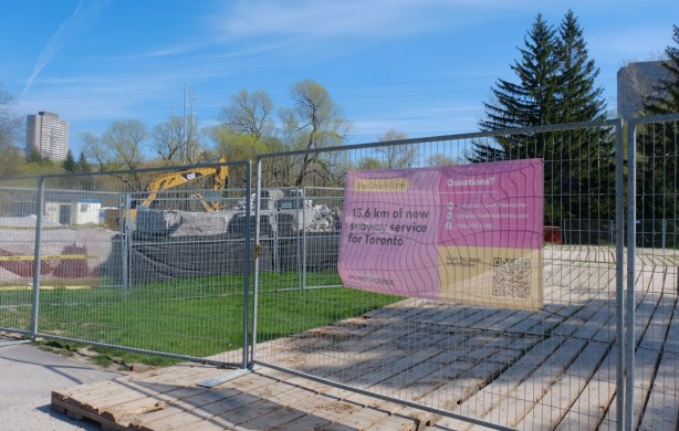 pink sign on construction fence in park that is for Ontario line, transit construction