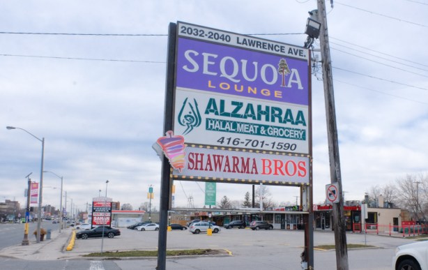 large billboard type sign in parking lot in front of strip mall, for Sequioa Lounge, Alzahraa halal grocer, and Shawarma Brothers, 