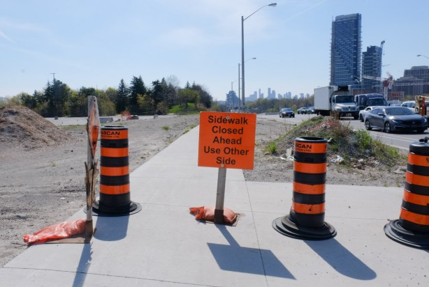 orange signs on sidewalk saying sidewalk closed ahead