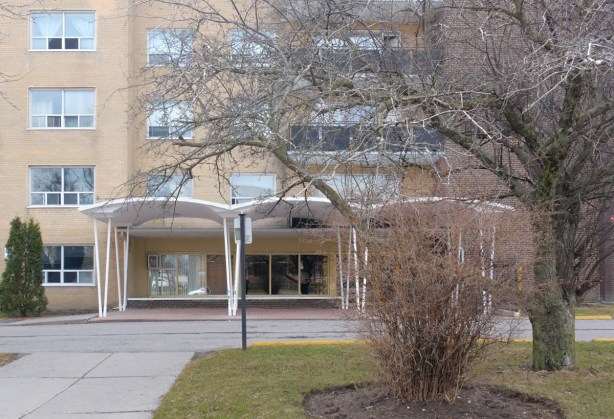 front of an apartment building, with entrance, from the 1970s, with wavy roof over the entrance