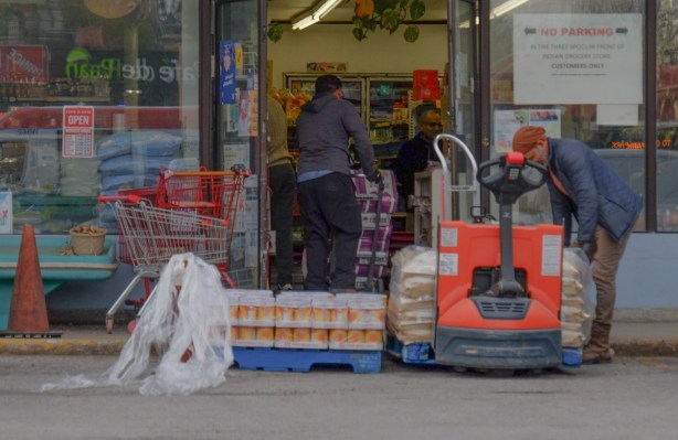 men unloading bags and boxes of groceries to an Asian, Indian, food store