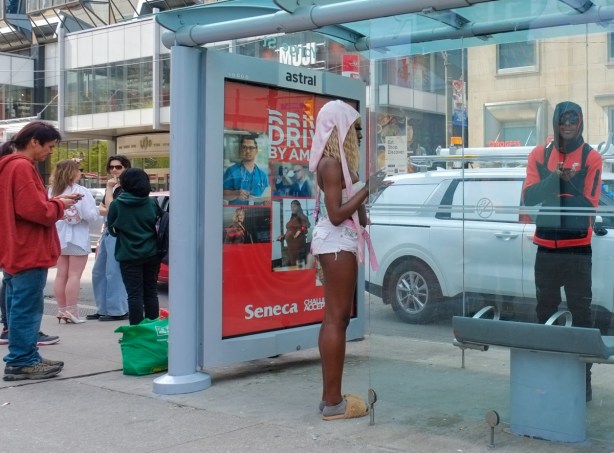 woman in short shorts and fuzzy brown slippers waits for a bus