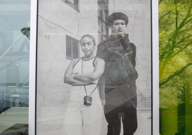 black and white photography, a couple standing outside a building, she in white sleeveless top and white pants, he in darker clothes