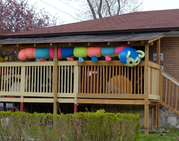 a large stuffed caterpillar on a deck of a house