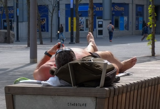 a man wearing only shorts lies on a bench