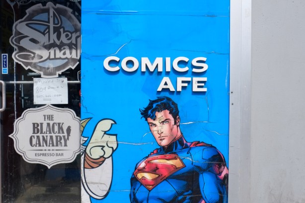 sign on Comics Cafe, store now closed, with C in Cafe missing, a picture of superman