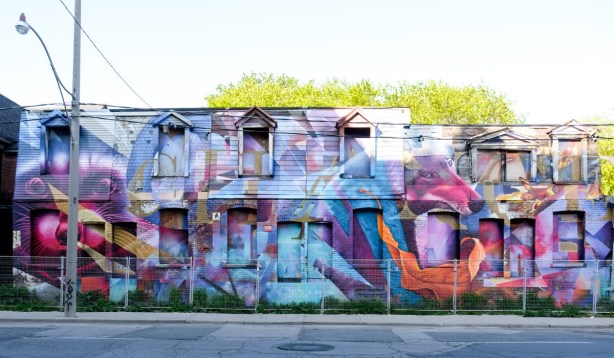 large street art painting by nick sweetman and luvs aka moises on a row of empty houses at Broadview and Eastern