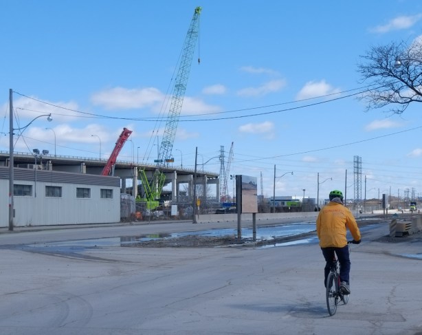 a man in a yellow Toronto jacket rides his bike down Villiers street