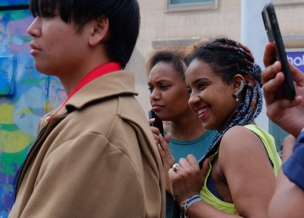two young women smiling as they watch street performer