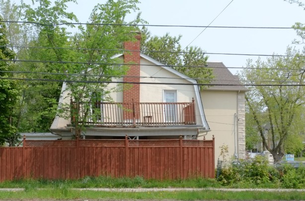 side view of a house, wood fence in front of it, roofline is barn shaped