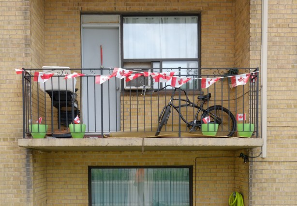 a balcony with a bike on it, also a garland of Canadian flags strung across the railing