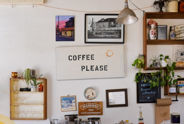 pictures and signs on the wall inside a coffee hop, First Last coffee, including a sign that says coffee please