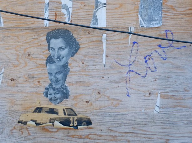 pasteups on a piece of plywood on a wall, car, three members of a family, mother, father, and daughter in a line, just their faces