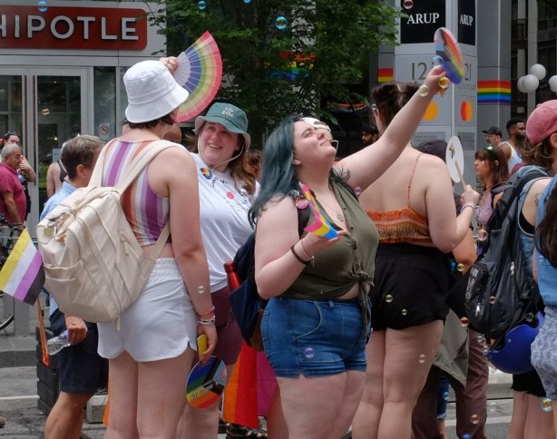 group pf women at dyke march in downtown toronto, with paper fans and playing withbubbles