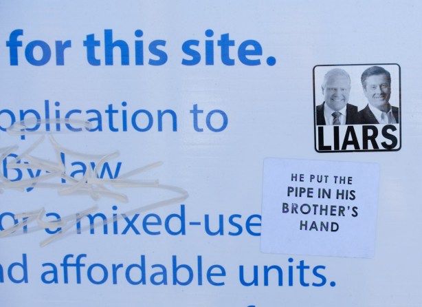 sticker on a city blue and white development notice sign, faces of Doug Ford and John Tory with the word Liars
