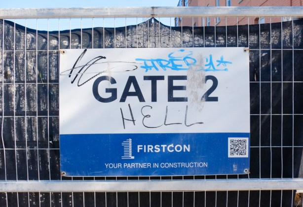 Construction site entrance sign that says gate 2. someone has added the word hell so that the sign now says gate to hell