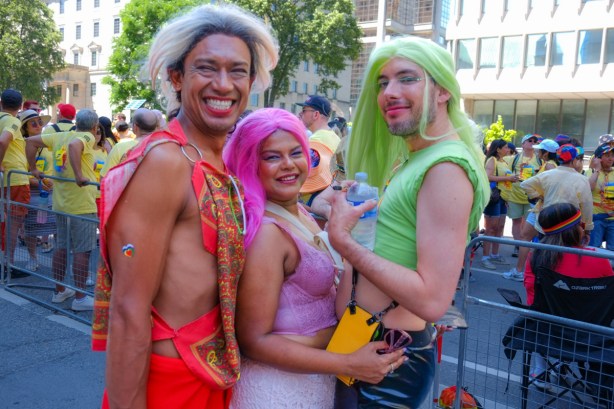 before parade, group of three people, one with long green hair and another with pink hair, posing, 