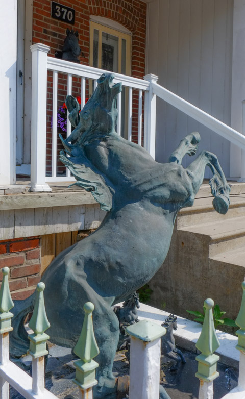 sculpture in a front yard of a horse up on its hind legs