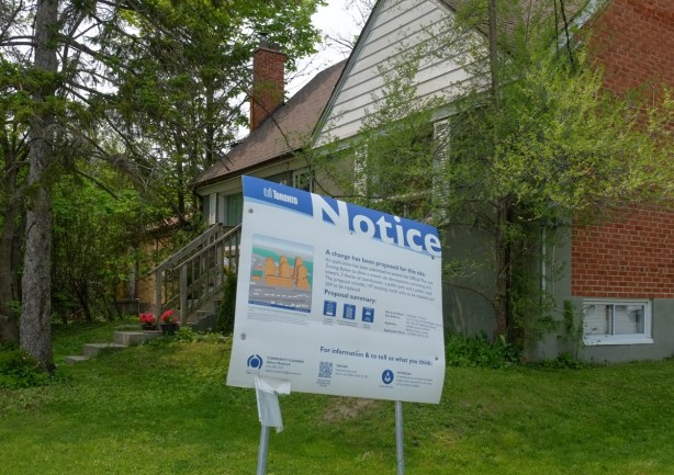 blue and white development notice in front yard of a house
