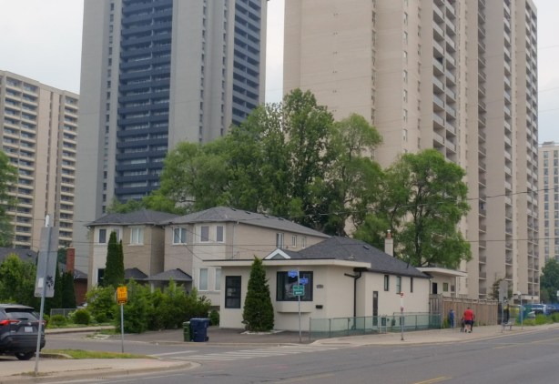 a few houses on a side street with taller apartment buildings behind