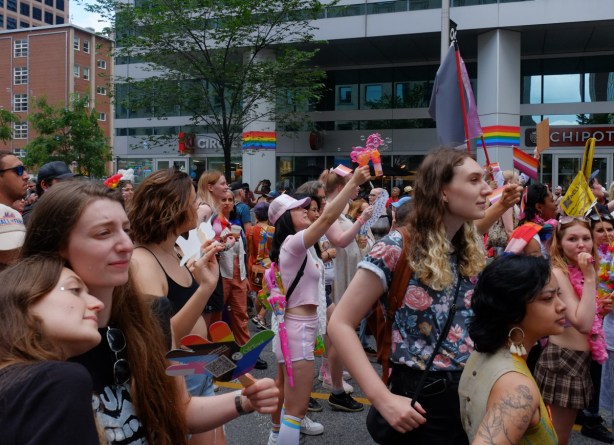 dyke march, pride toronto, people walking in parade, some with bubble blowing guns, some with flags