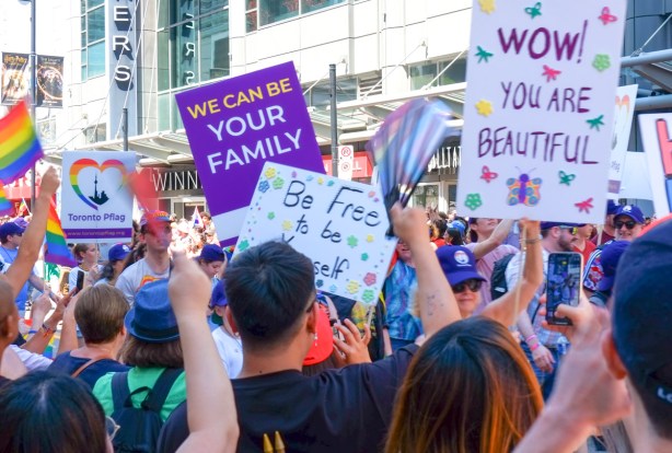pflag group in pride parade, with signs saying we can be your family, and you are beautiful, 