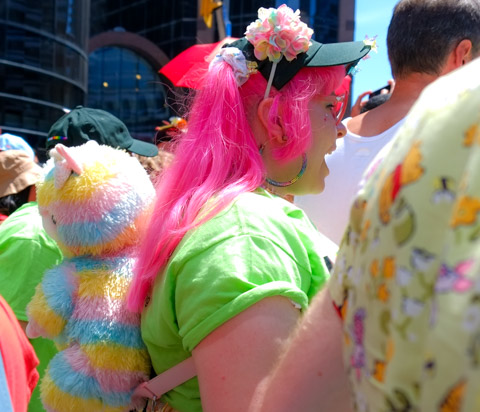 young woman with bright pink hair and a rainbow teddy bear in her backpack 