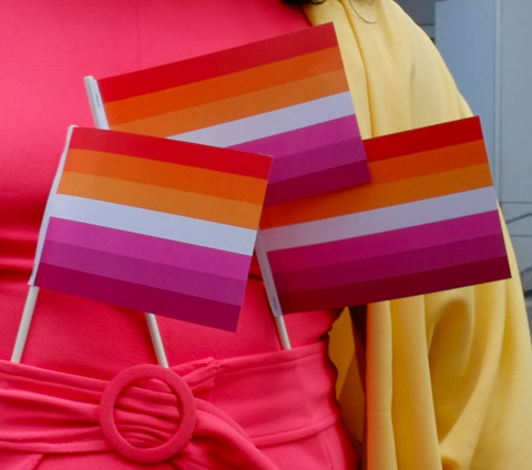 3 little orange, white, and pink striped flags tucked into the waistband of a pink dress