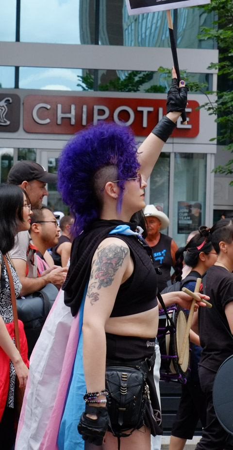 dyke march, person with purple mohawk hairdo 