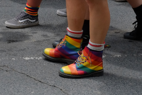 a pair of rainbow boots, with white ankle socks, in dyke march