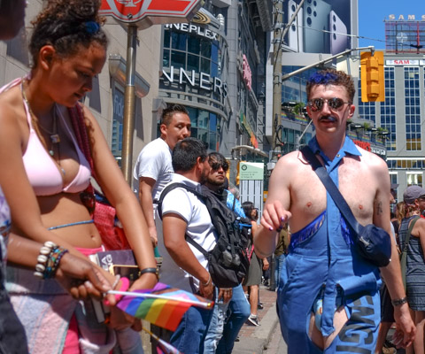 man walking on sidewalk in blue overalls with crotch removed