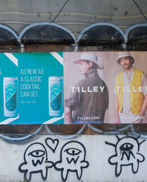 a poster on a construction site for Tilley clothing, graffiti too