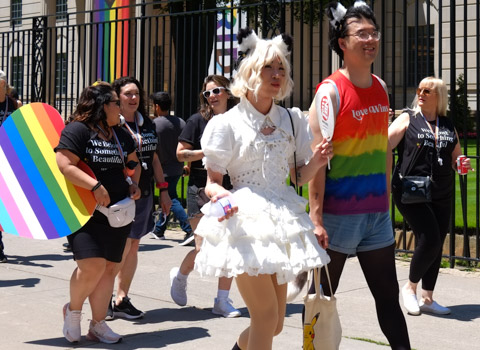 before pride parade, man in drag, white frilly dress with bow in hair