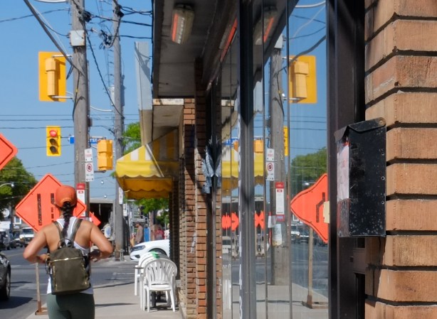 a woman with a backpack walks by a window with many reflections in it