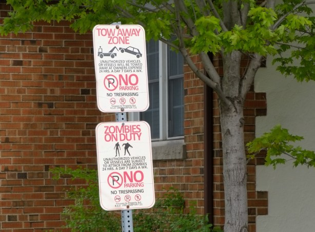 no parking signs, one says zombies on duty