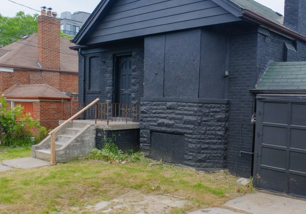 empty brick house, boarded up and painted black, all black