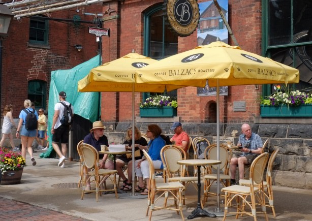 people sitting outside at balzacs coffee at distillery district, yellow umbrellas, 