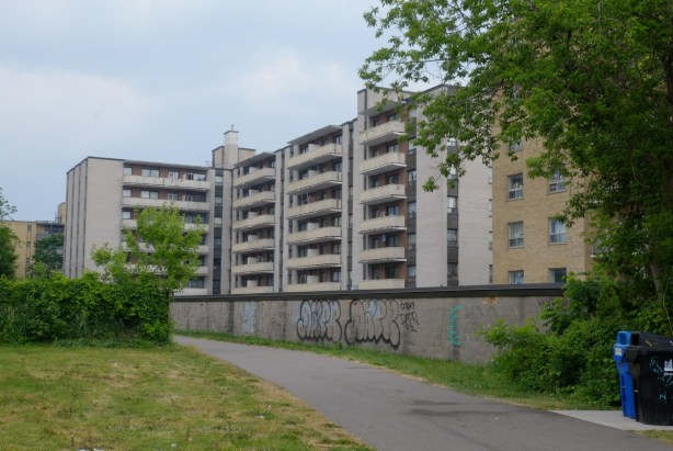 back of apartment building with concrete balconies, as seen from the Belt Line trail
