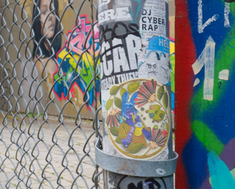 stickers on pole, including one that looks like an angry white cloud, a drawing in a circle shape by catchoo