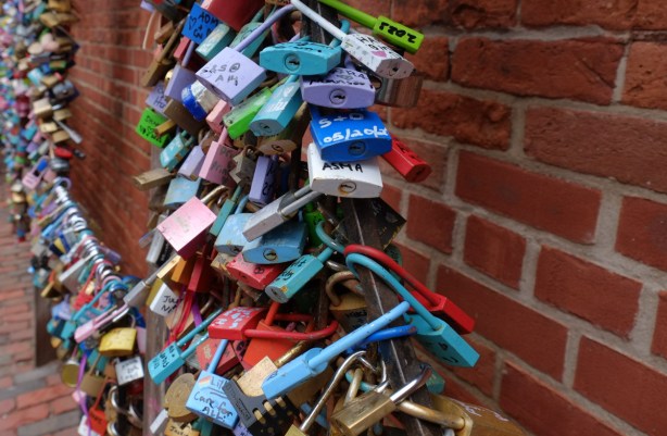 locks attached to a metal structure on a brick wall, love sign in distillery