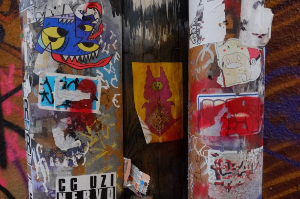 many stickers and small wheatpaste on a wall, many colourful pieces