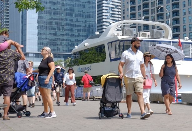 on the waterfront, people walking past small lake cruise boat