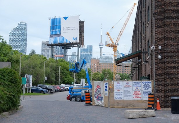 view at south end of Distillery, just north of Gardiner, looking west towards CN Tower, many cranes, large billboard
